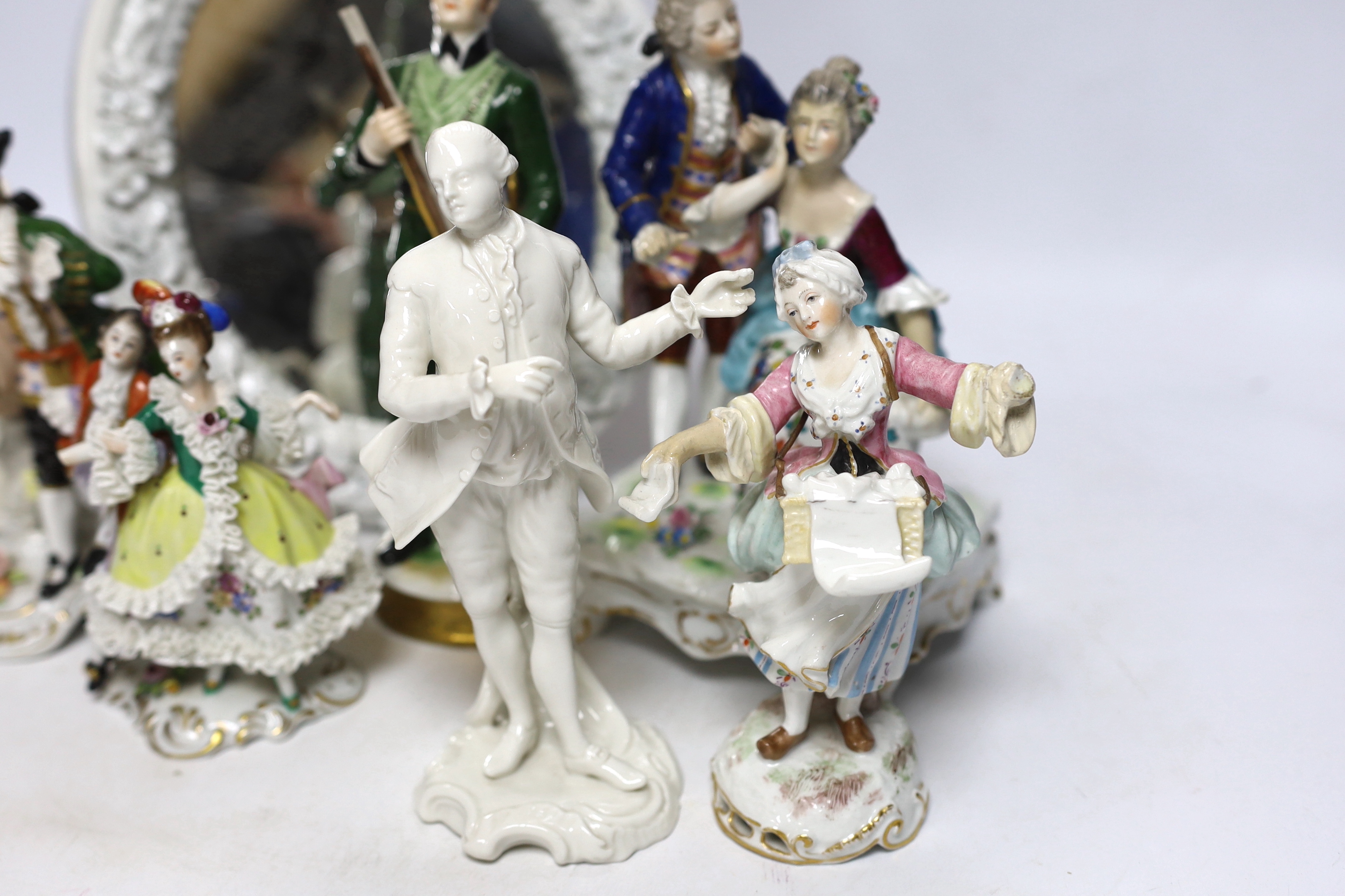 Seven Continental porcelain figures and an oval mirror with floral encrusted decoration, 27cm high